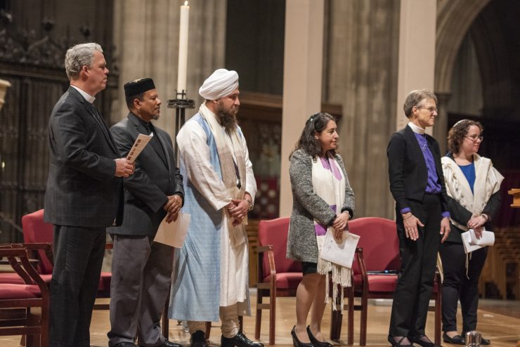Representatives of several different religions and traditions stand together on a platform.
