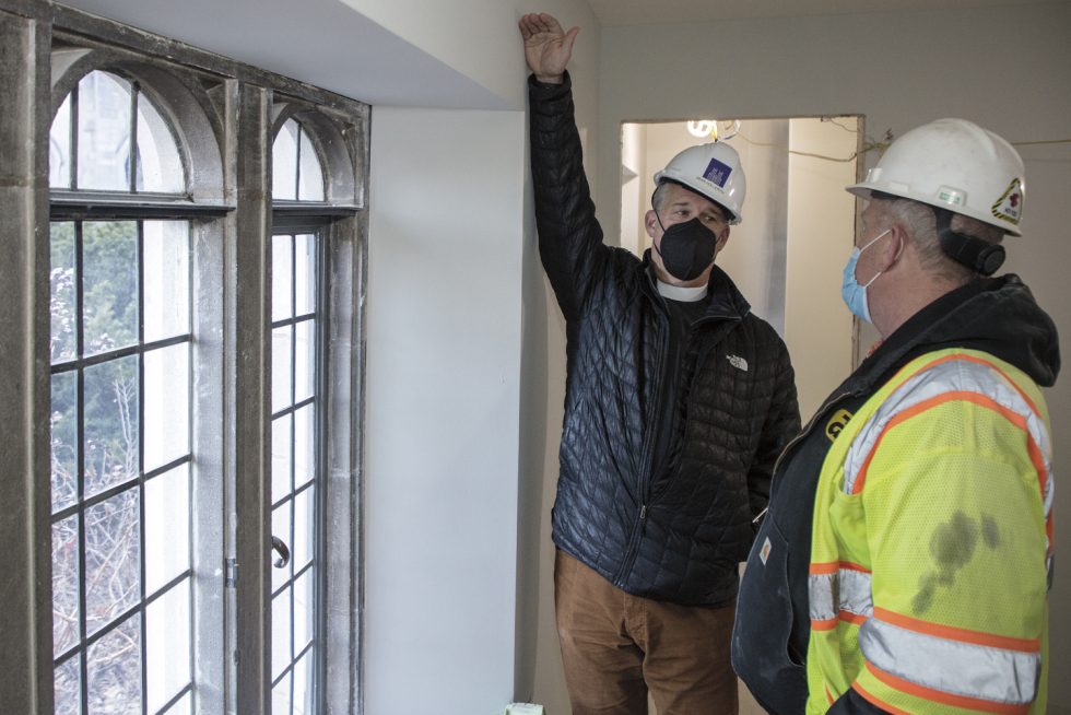 Cathedral Dean Randy Hollerith, wearing a construction hat, gestures while on a tour of the building.