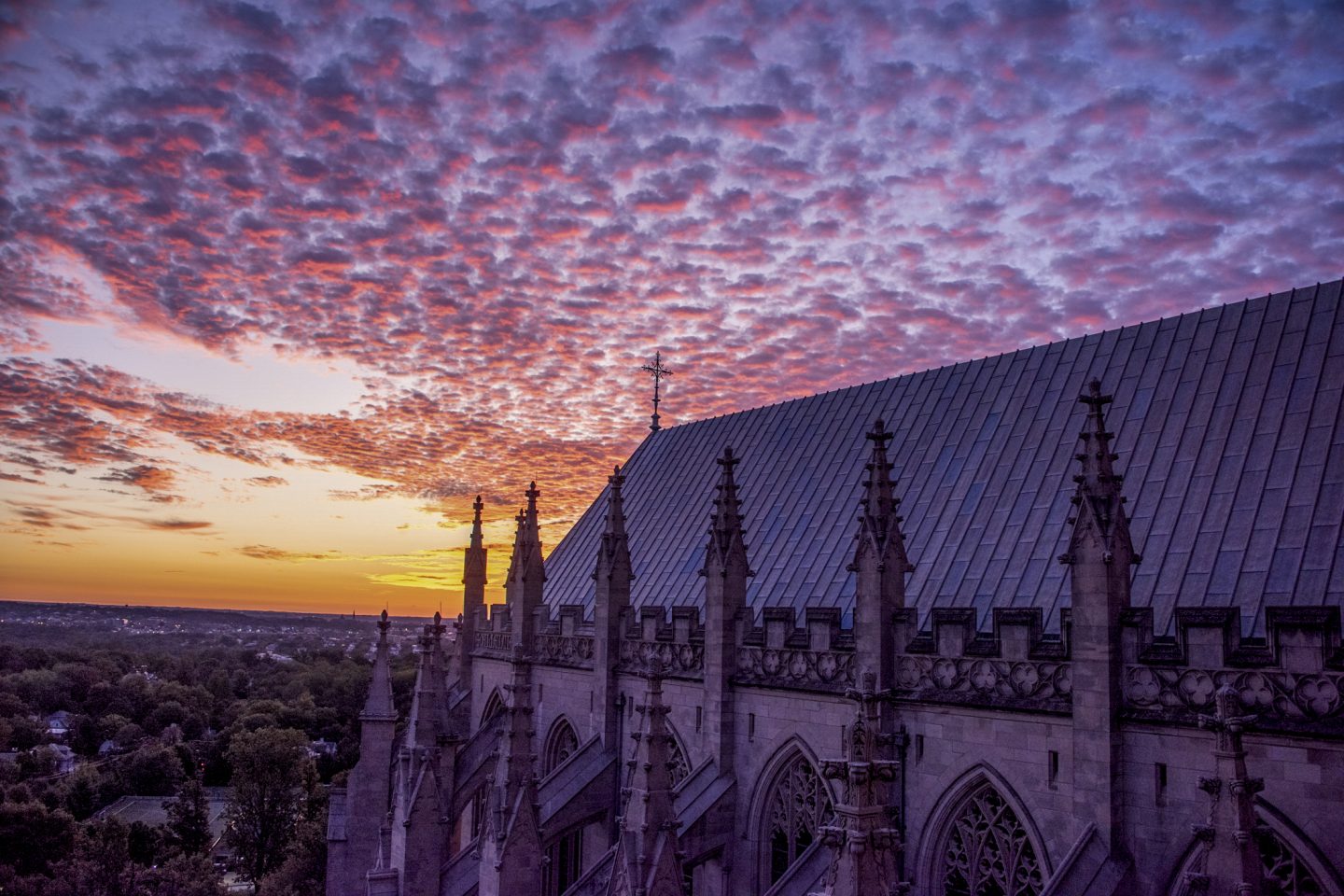 Orange, yellow, pink, and purple colors at sunrise extend to the east of the Cathedral.