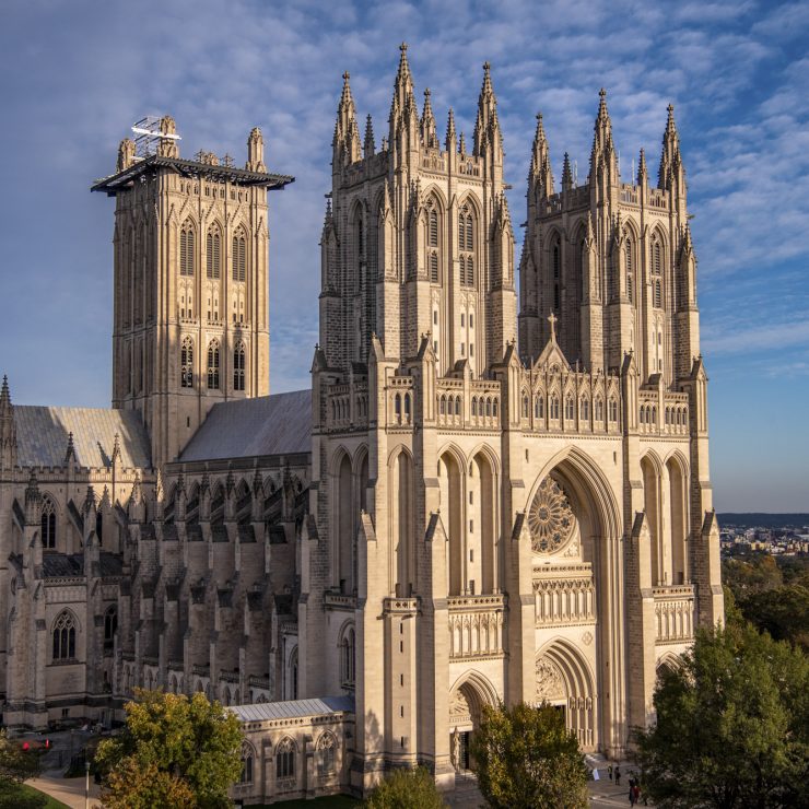 The gothic Cathedral's limestone architecture glows in the late afternoon sun in front of a blue sky.