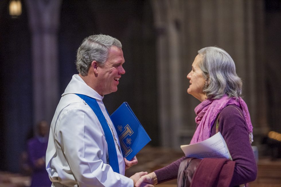 Cathedral Dean Randy Hollerith shakes hands with a woman after a worship service.