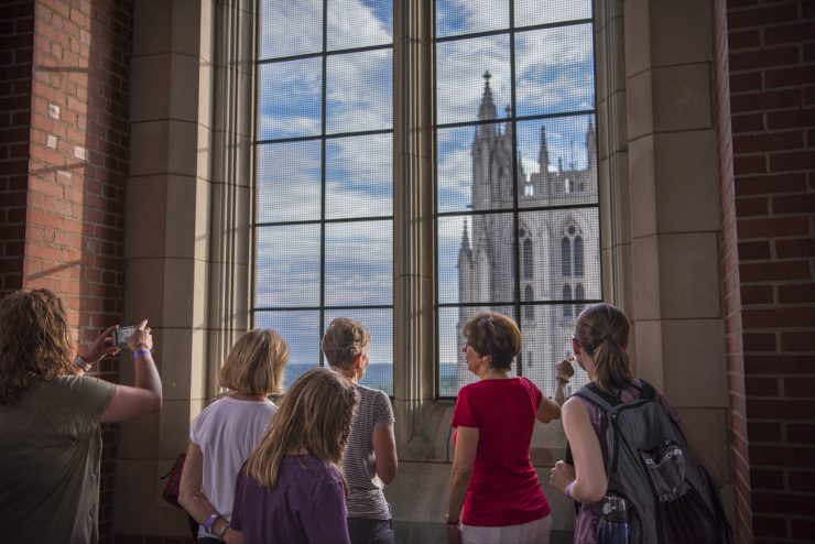 A docent talks to a tour group and points out a large window in the bell tower at the Cathedral's central tower.